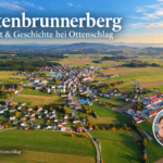 Gutenbrunnerberg – výhľad a história v Ottenschlagu – rekreačné apartmány v Gutenbrunne Prehľad obce Ottenschlag vygenerovaný umelou inteligenciou, obsahujúci polia, lesy a fotografický odznak Anny a Herberta.