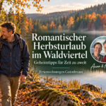 Romantická podzimní dovolená ve Waldviertelu – skryté tipy – Apartmány Gutenbrunn Pár na dovolené se prochází ruku v ruce u podzimního lesního jezera, vedle nich jsou na fotografii Anna a Herbert.