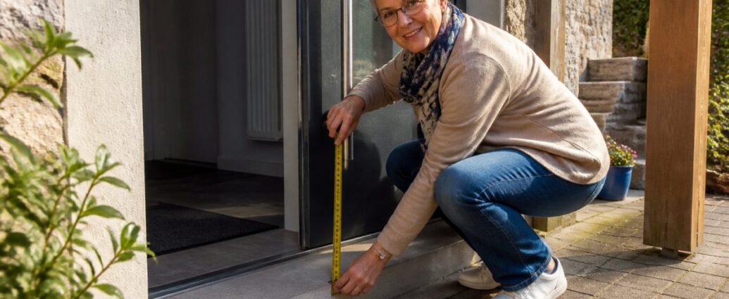 accessible-accommodation-checking-doors-and-steps-1791792920 - Gutenbrunn Vacation Rentals A woman crouching by an open front door, measuring the threshold with a tape measure outside.