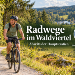 Jízda na kole ve Waldviertelu mimo hlavní silnici – prázdninové apartmány Anny a Herberta – Prázdninové apartmány Gutenbrunn Dva cyklisté na klidné stezce vedoucí lesem a loukami, vedle nich Anna a Herbert na fotografické plackě.